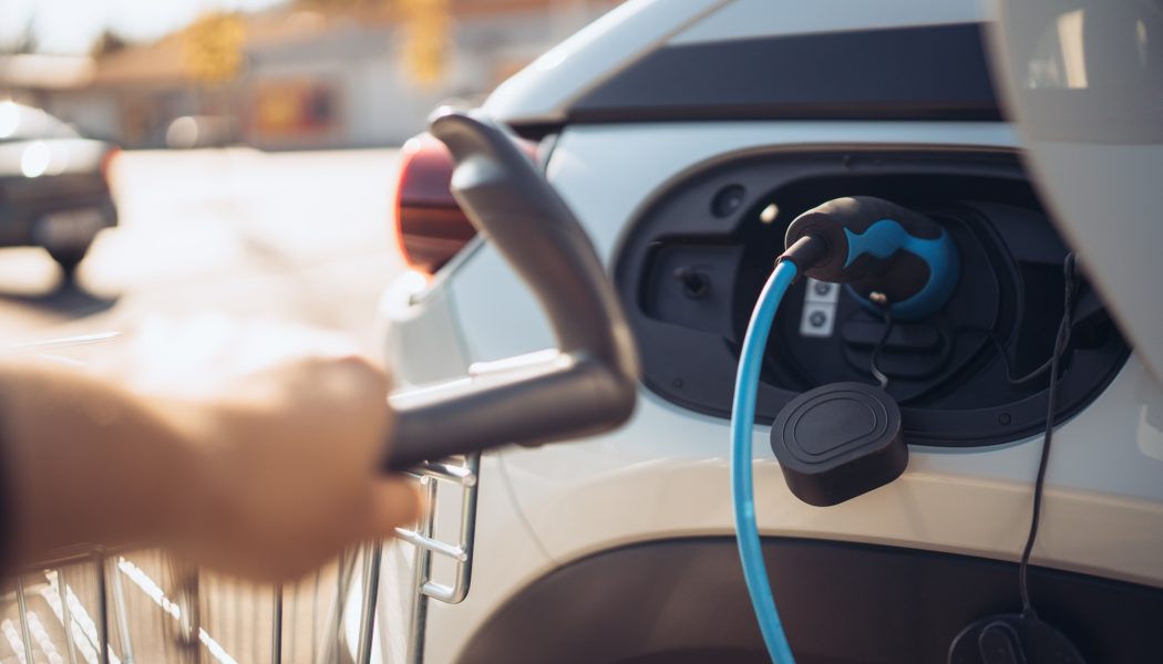 Close-up of charging electric car at supermarket parking.